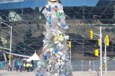 sculpture of plastic bottles coming out of a large faucet
