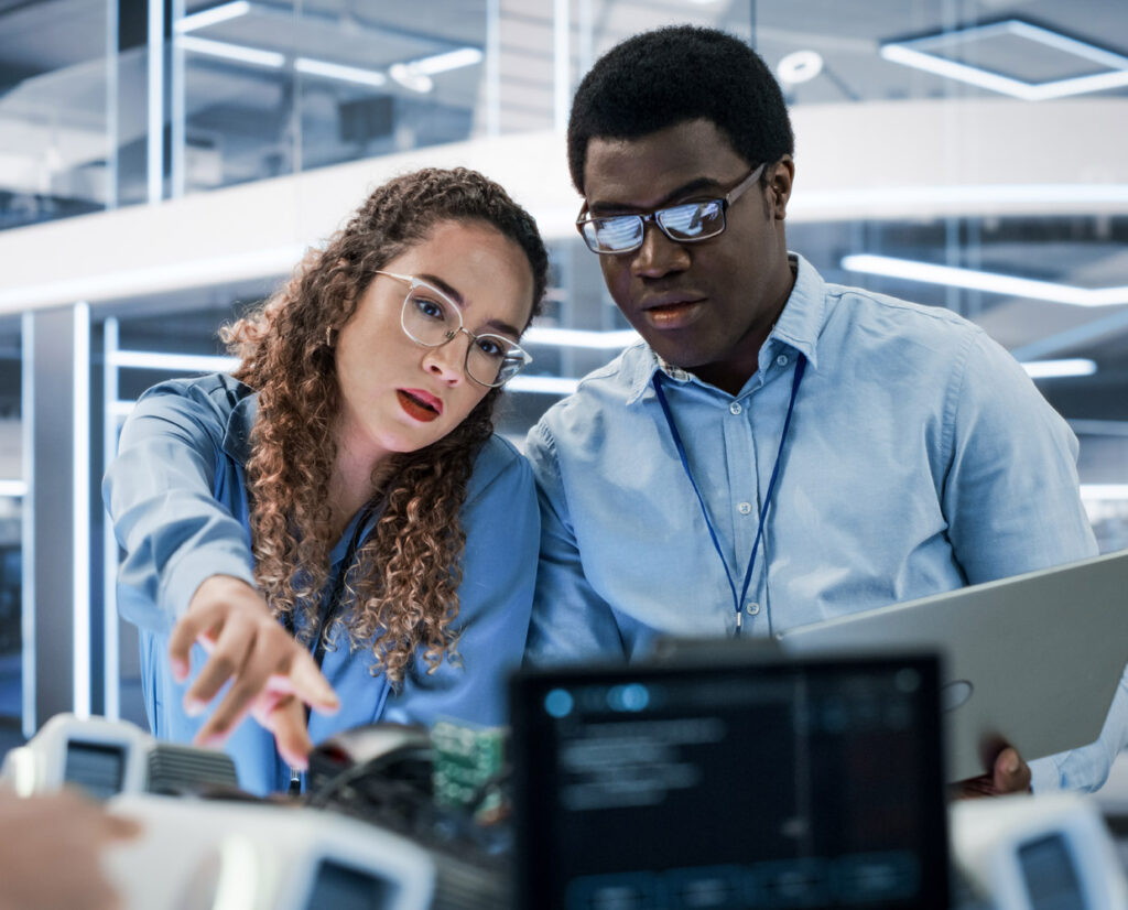 Two engineers looking at a laptop together, discussing solutions.