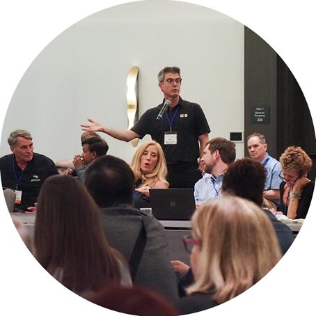 a man speaking in front of a microphone at a conference