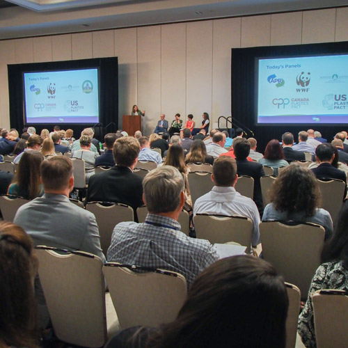 photo of people sitting in an audience with a panel of people on stage