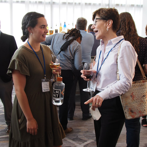 Two people holding wine glasses and talking