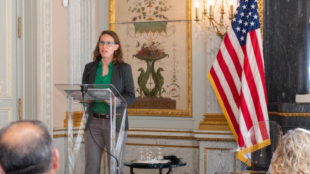 APR Chief Policy Officer Kate Bailey speaking next to a US flag