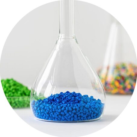 three scientific flasks filled with colored plastic pellets